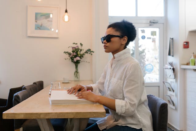 blind person sitting at a table reading a braille book