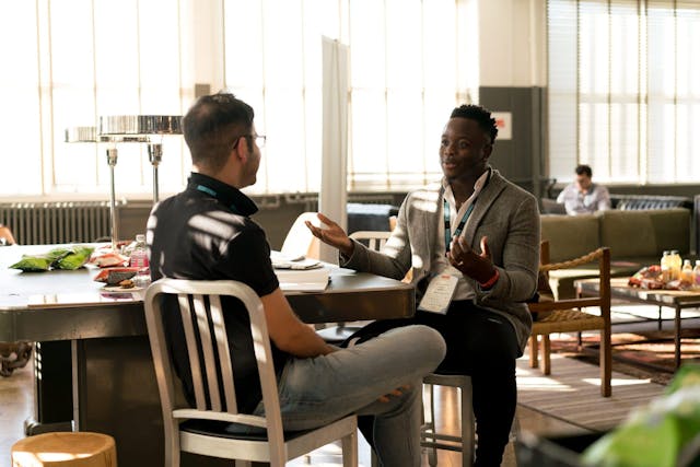 Two people sitting across from each other at a table while talking