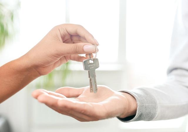 person holding out a set of keys to another person